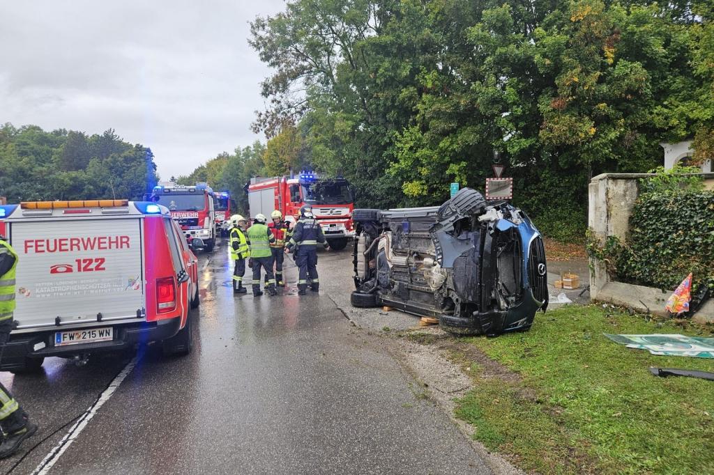 FF Bad Fischau: Fahrzeugbergung mit Menschenrettung - verunnfaltes Fahrzeug liegt auf der Seite mit Einsatzkräften und Feuerwehrfarhzeugen